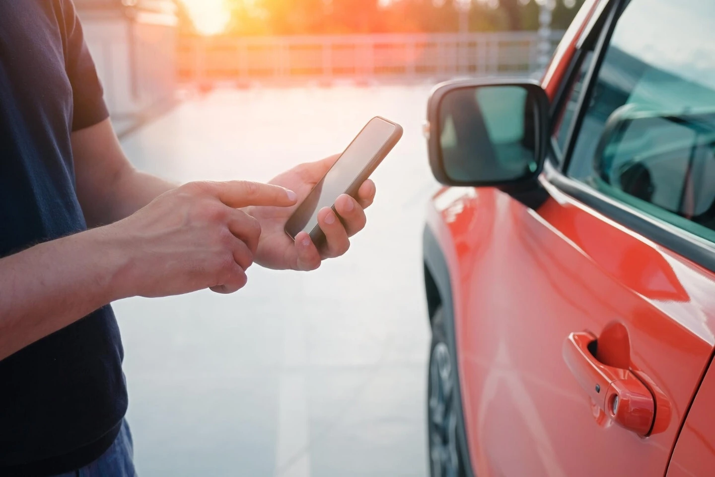A contented person in a suit standing next to a red car in front of a view of the CarVerification website