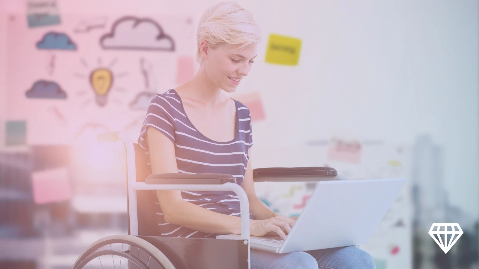 Person in wheelchair using a laptop in a creative workspace.